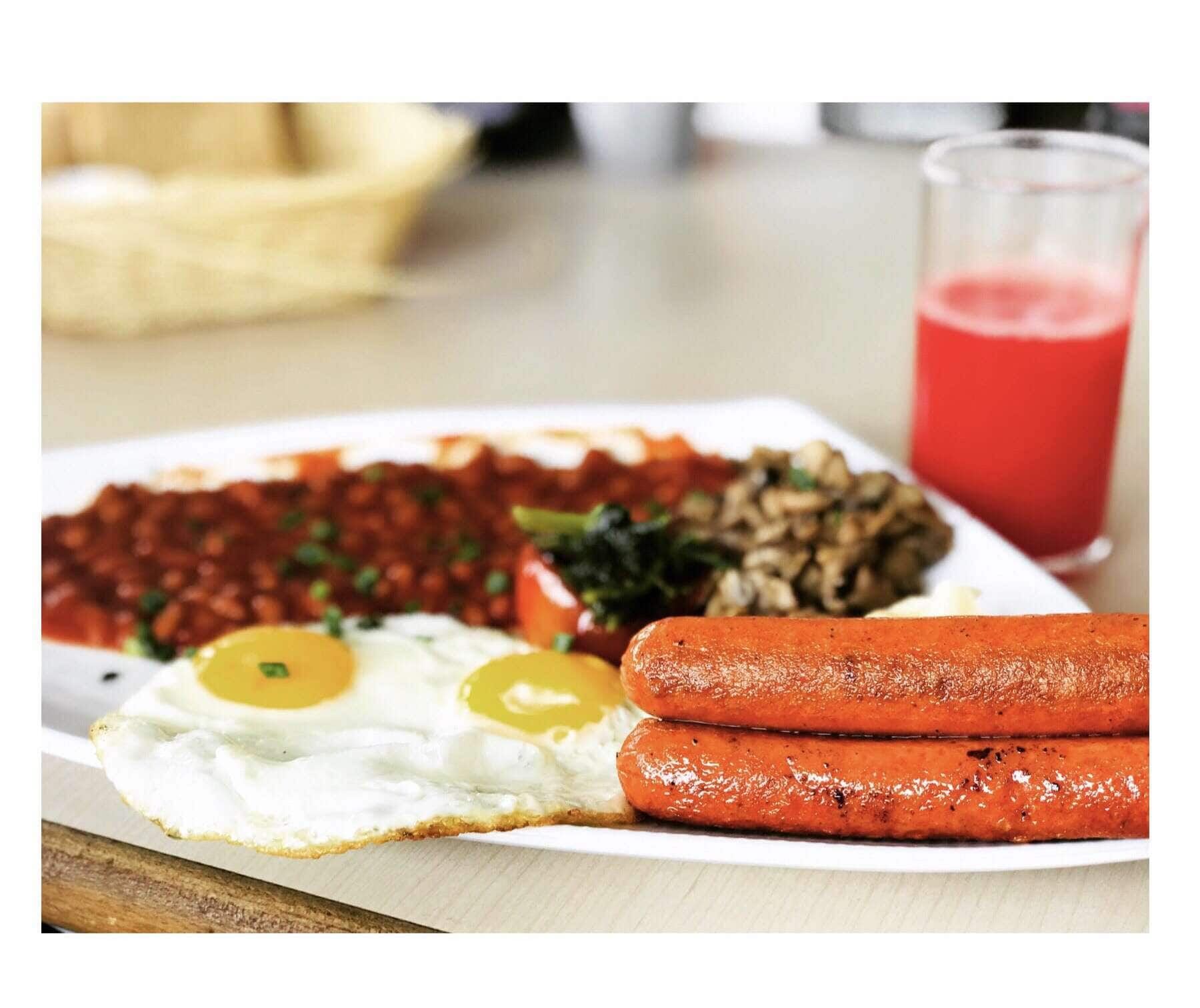 Sausages, fried eggs and beans with a glass of watermelon juice