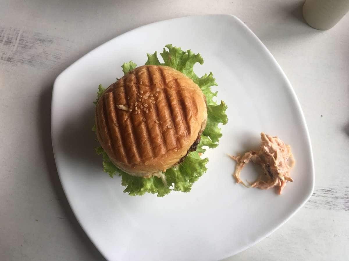 A tall burger on a white plate