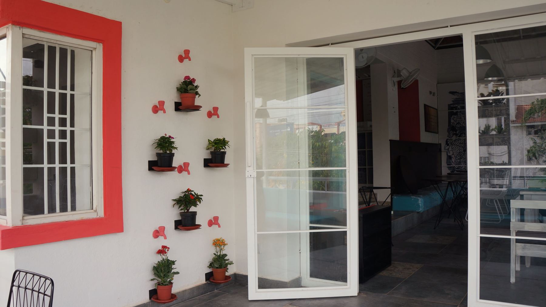 Red window frames and potted plants at the entrance